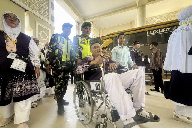 Petugas membantu jamaah calon haji kelompok terbang (kloter) pertama tiba di embarkasi Kertajati, Kabupaten Indramayu, Jawa Barat, Kamis (1/5/2025). Foto: kumparan