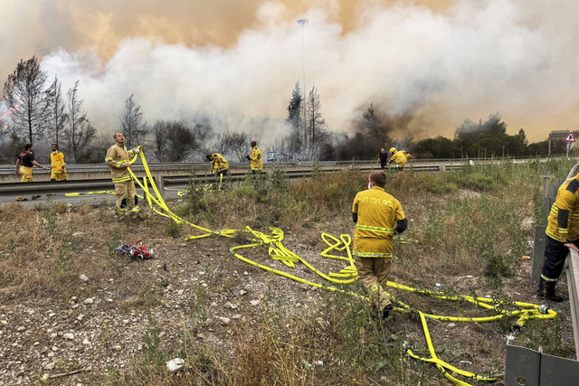Petugas pemadam kebakaran Israel bekerja di dekat Latrun saat kebakaran hutan akibat panas dan angin yang ekstrem terjadi di Israel tengah, Rabu (30/4/2025). Foto: Sinan Abu Mayzer/REUTERS