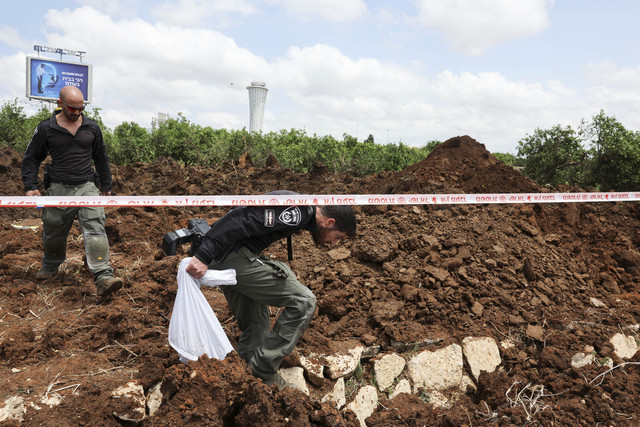 Petugas polisi Israel menyelidiki kawah di lokasi serangan rudal yang diluncurkan dari Yaman, dekat Bandara Ben Gurion, di Tel Aviv, Israel, Minggu (4/5/2025). Foto: Nir Elias/REUTERS