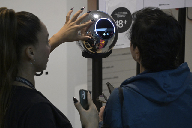 Seorang wanita menjalani pemindaian iris mata dengan sebuah bola mata, perangkat pemindai data biometrik, untuk ditukar dengan mata uang kripto Worldcoin di Buenos Aires (22/3/2024). Foto: Juan Mabromata/AFP