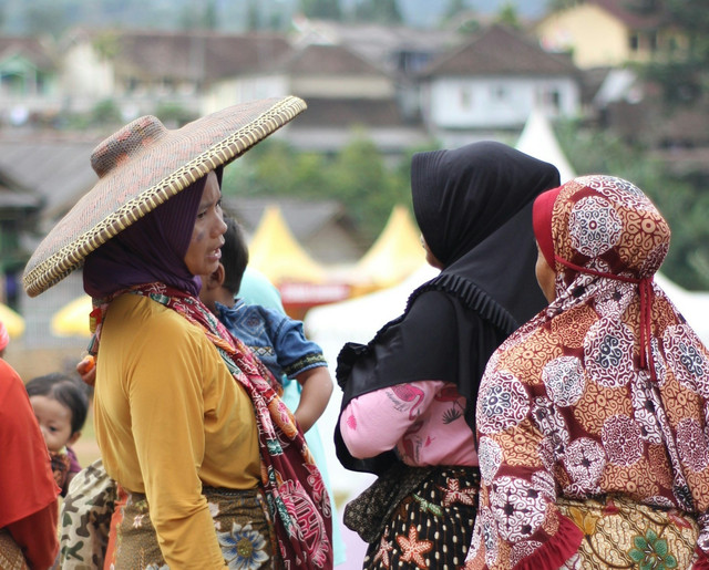 Potret ibu-ibu yang menggendong anak kecil sedang mengobrol dengan temannya. Foto oleh Arif Wijaksana/unsplash