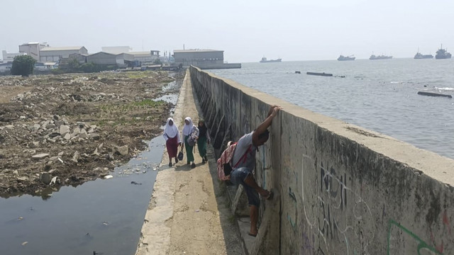 Anak berjalan di sekitar tanggul menuju rumah mereka di RT 14/RW 15 Muara Baru, Penjaringan, Jakut, Selasa (6/5/2025). Foto: Thomas Bosco/kumparan