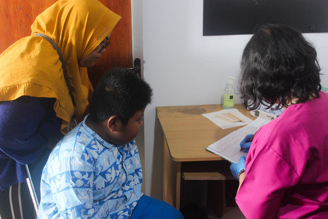 Seorang ibu menemani anaknya dalam pemeriksaan kesehatan oleh dokter di PAUD Sehat Ceria Bojongnggede, 5 Mei