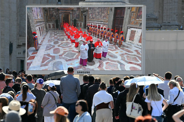 Layar di Lapangan Santo Petrus yang memperlihatkan para Kardinal di Kapel Sistine menjelang konklaf untuk memilih Paus berikutnya di Vatikan, Selasa (7/5/2025). Foto: Andreas SOLARO / AFP
