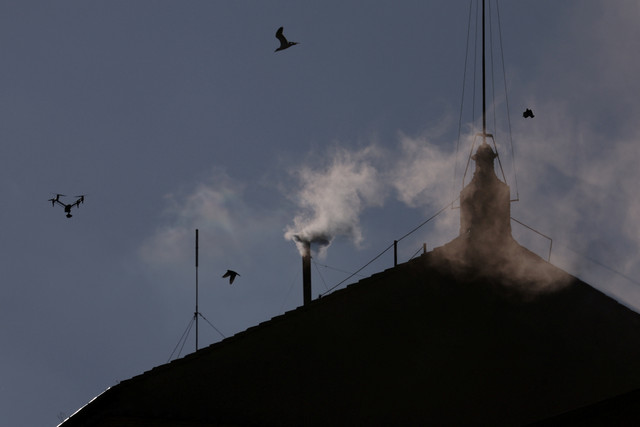 Asap putih mengepul dari cerobong asap Kapel Sistina, menandakan bahwa seorang paus baru telah terpilih di Vatikan, Kamis (8/5/2025). Foto: Hannah McKay/REUTERS