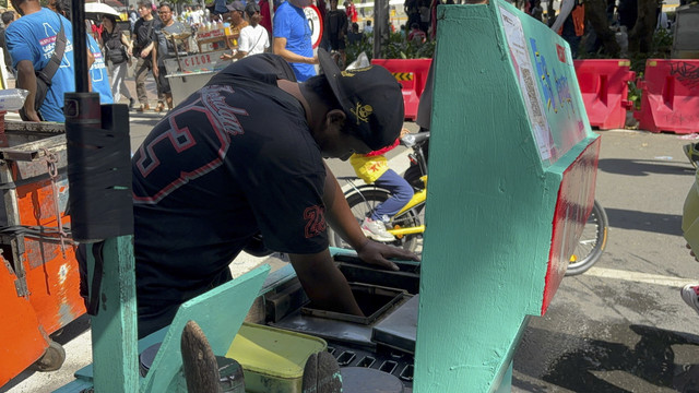 Aden (30), menjual jajanan jadul es goyang di kawasan CFD Sudirman-Thamrin, Jakarta Pusat pada Minggu (11/5/2025). Foto: Abid Raihan/kumparan