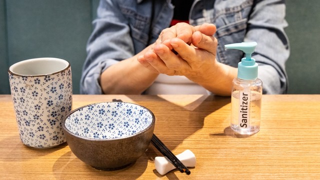 Ilustrasi membersihkan tangan dengan sanitizer sebelum makan di restoran. Foto: ThamKC/Shutterstock