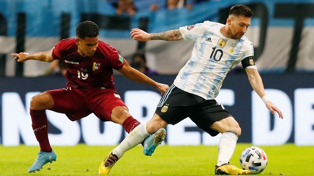 Pemain Argentina Lionel Messi beraksi dengan pemain Venezuela Miguel Navarro, di Estadio La Bombonera, Buenos Aires, Argentina, Jumat (25/3/2022). Foto: Agustin Marcarian/REUTERS