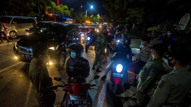 Petugas kepolisian memeriksa pengendara yang hendak memasuki Kota Banjarmasin saat sosialisasi pemberlakuan pengetatan di Pos PPKM Jalan Ahmad Yani Km 6, Banjarmasin, Kalimantan Selatan. Foto: Bayu Pratama S/ANTARA FOTO