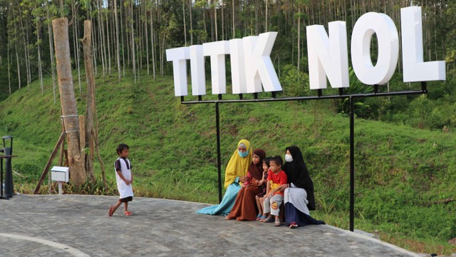 Sebuah keluarga sedang duduk di bawah tulisan identitas titik nol IKN, Jumat (18/3/2022). Foto: Agaton Kenshanahan/kumparan