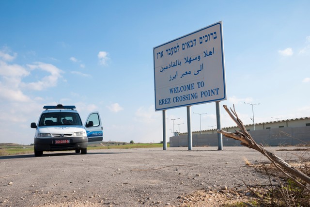 Kendaraan polisi Israel diparkir di sebelah tanda bertuliskan "Selamat datang di Erez Crossing Point", pintu masuk dari Israel ke Jalur Gaza.  Foto: Joel Carillet/Getty Images