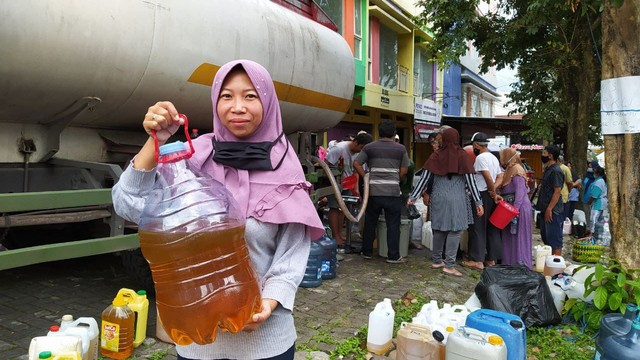 Wajah sumringah Novalia Ardian (30) salah satu PKL Alun-Alun Kota Batu usai mendapat minyak goreng dengan harga murah. Foto/Azmy