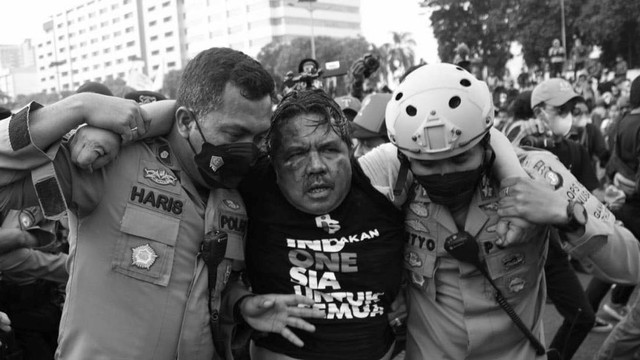 Polisi membawa Ade Armando yang terluka saat demo 11 April di Gedung DPR RI, Jakarta, Senin (11/4). Foto: Aditia Noviansyah/kumparan