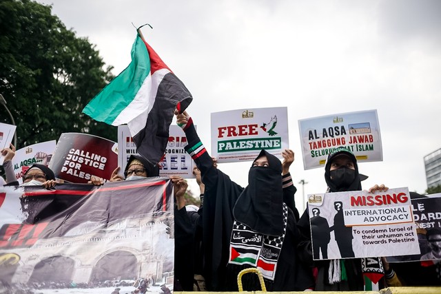 Para wanita dari Lembaga kemanusiaan Aqsa Working Group (AWG) mengibarkan bendera Palestina saat Aksi Bela Al-Aqsa di Jalan Medan Merdeka Selatan, Jakarta pada Rabu (20/4/2022). Foto: Iqbal Firdaus/kumparan