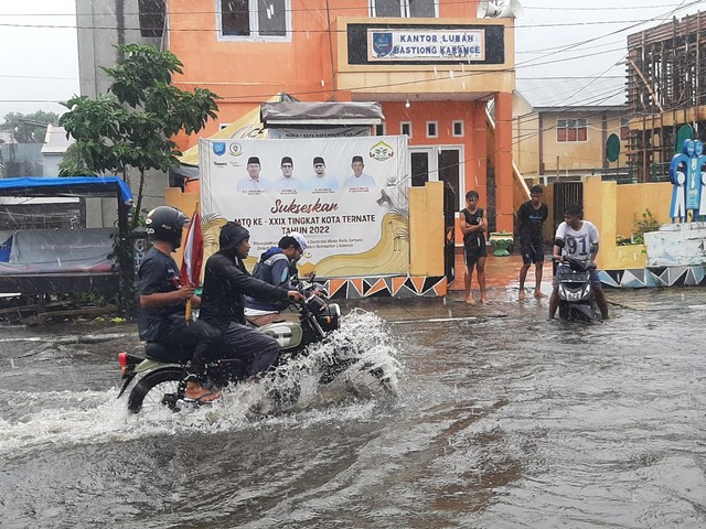 Sejumlah pengendara terpaksa menjalankan kendaraannya melewati air. Karena, kondisi badan jalan di Kelurahan Bastiong Karance, Ternate Selatan, Kota Ternate terendam saat terjadi hujan pada Minggu (20/2). Foto: Dealfrit Kaerasa/JMG