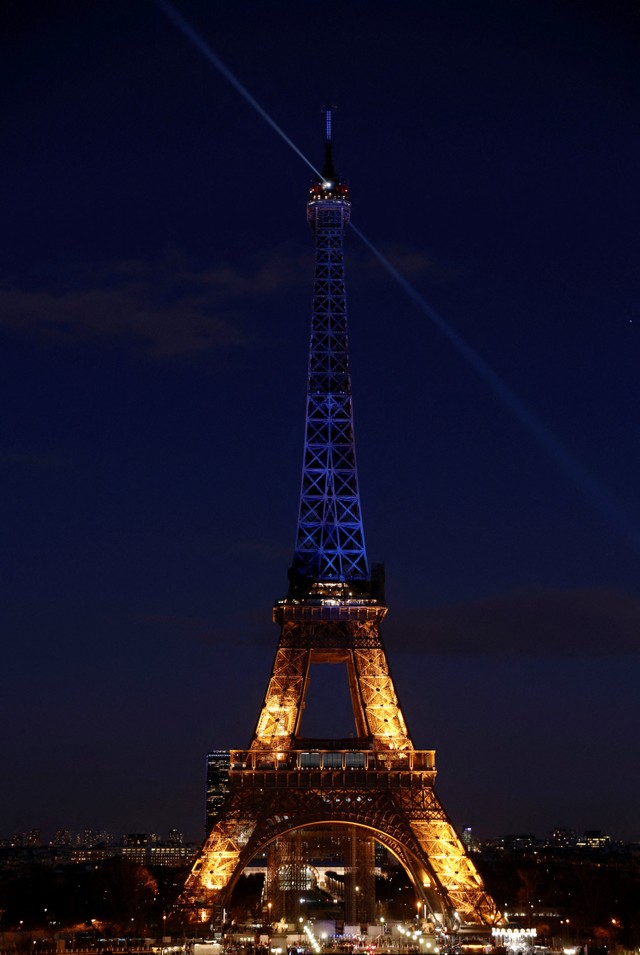 Menara Eiffel dinyalakan dengan warna biru dan kuning, warna bendera Ukraina, untuk mendukung rakyat Ukraina setelah Rusia melancarkan operasi militer besar-besaran terhadap Ukraina, di Paris, Prancis. Foto: Benoit Tessier/REUTERS