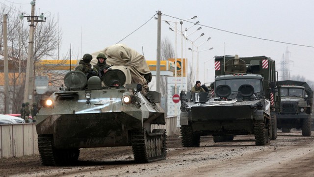 Prajurit naik di atas kendaraan lapis baja Rusia di Armyansk, Krimea, Jumat (25/2/2022). Foto: Stringer/AFP