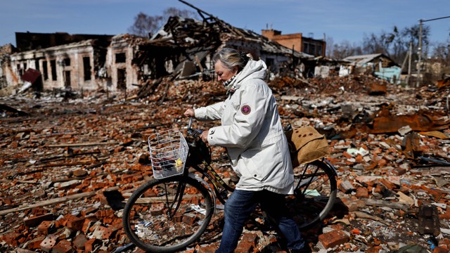 Warga berjalan melewati bangunan yang hancur akibat dirudal udara pasukan Rusia di Trostianets, wilayah Sumy, Ukraina, Jumat (15/4/2022). Foto: Zohra Bensemra/Reuters