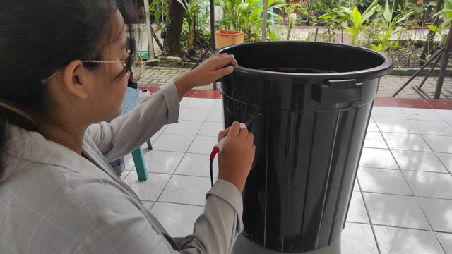 Melubangi media budidaya ikan dan kangkung agar air yang masuk tidak berlebihan dan menyebabkan gagal panen. Sumber: Dokumentasi pribadi kelompok 88