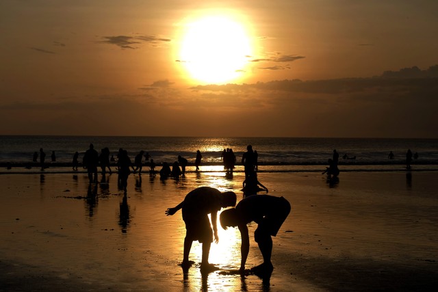 Wisatawan menikmati pemandangan matahari terbenam saat liburan Hari Raya Idul Fitri 1443 H di Pantai Kuta, Badung, Bali, Senin (2/5/2022). Foto: Nyoman Hendra Wibowo/Antara Foto