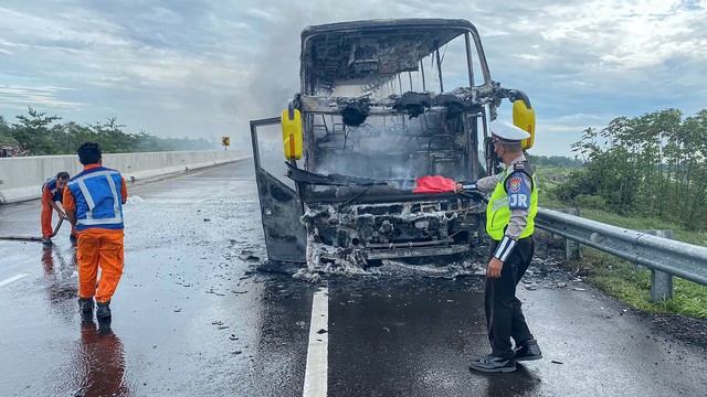 Petugas mengamankan bus bernopol K 1670 EW yang terbakar di Tol Pandaan Pasuruan KM 60-800, Jawa Timur, Minggu (6/3/2022). Foto: Dok. PJR Polda Jatim