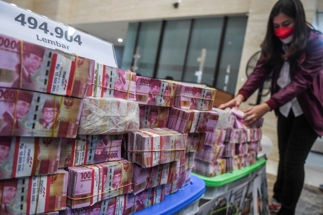 Petugas kepolisian menata barang bukti uang palsu saat rilis pengungkapan kejahatan mata uang palsu di Bareskrim Mabes Polri, Jakarta, Selasa (1/3/2022). Foto: Galih Pradipta/ANTARA FOTO