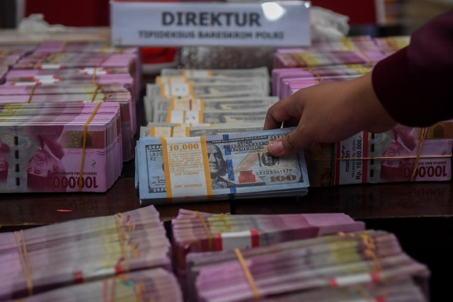 Petugas kepolisian menata barang bukti mata uang dolar palsu saat rilis pengungkapan kejahatan mata uang palsu di Bareskrim Mabes Polri, Jakarta, Selasa (1/3/2022).  Foto: Galih Pradipta/ANTARA FOTO