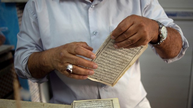 Relawan di Libya melakukan restorasi Al-Quran yang dimakan usia. Foto: Nada Harib/REUTERS