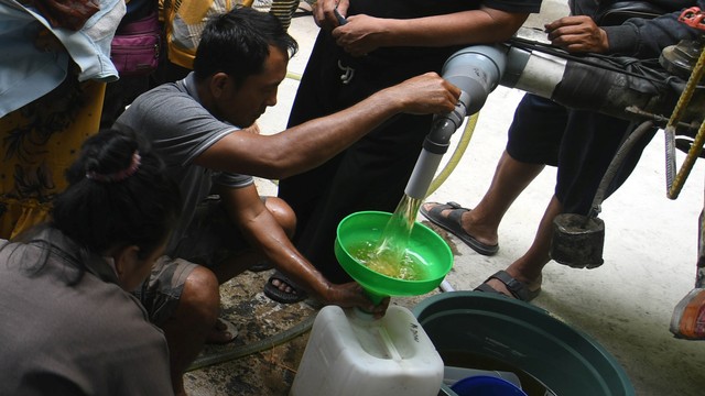 Petugas melayani warga yang antre untuk membeli minyak goreng curah di Palu, Sulawesi Tengah, Rabu (6/4/2022). Foto: Mohamad Hamzah/Antara Foto