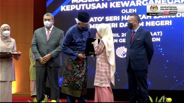 Rohana Abdullah (22) menghapus air matanya saat menerima surat kewarganegaraan Malaysia dari Mendagri Datuk Seri Hamzah Zainuddin. Foto: Facebook/hamzahzainudinofficial