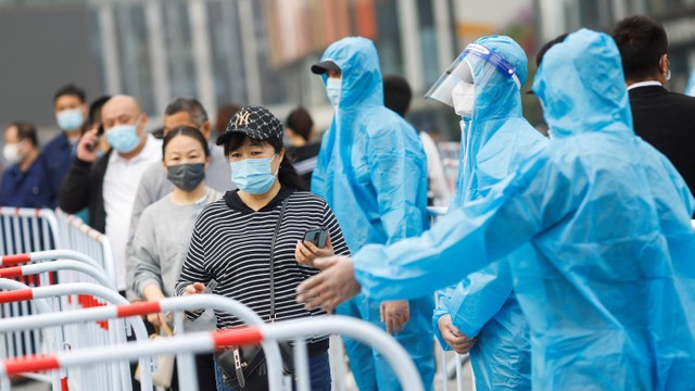 Petugas menggunakan Alat Pelindung Diri (APD) lengkap mengarahkan warga yang akan melakukan swab tes massal di Beijing, China, Senin (25/4/2022). Foto: Carlos Garcia Rawlins/REUTERS