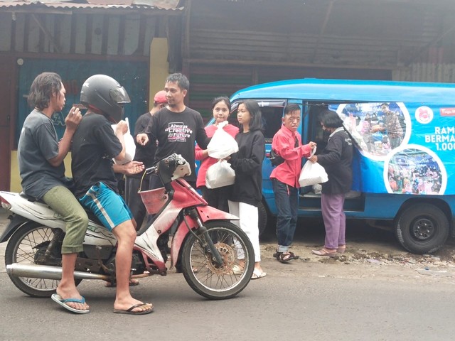 Pengendara sepeda motor tampak semringah mendapatkan paket buka puasa dan gula yang diberikan Tugu Media Group, pada Jumat (22/04/2022). Foto: Dwi Lindawati