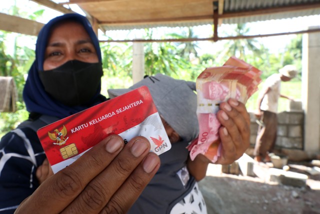 Warga penerima manfaat memperlihatkan kartu keluarga sejahtera dan uang bantuan sosial (bansos) program sembako tahun 2022 dari Kementerian Sosial (Kemensos) di Banda Aceh, Aceh, Minggu (20/2/2022). Foto: Irwansyah Putra/ANTARA FOTO