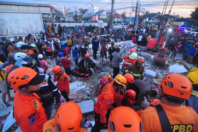 Tim SAR mengevakuasi korban yang terjebak di reruntuhan gedung retail modern Alfamart di Gambut Km 15, Kabupaten Banjar, Kalimantan Selatan, Senin (7/1/2021).  Foto: Iman Satria/ANTARA FOTO