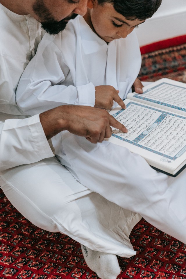 Ayah dan anak mengisi Ramadan dengan membaca Al-qur'an (sumber: www.pexels.com)