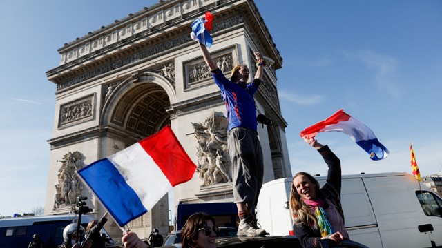 Para pengunjuk rasa mengibarkan bendera Prancis saat konvoi kendaraan untuk memprotes vaksin dan pembatasan di Paris, Prancis, Sabtu (12/2/2022). Foto: Benoit Tessier/REUTERS