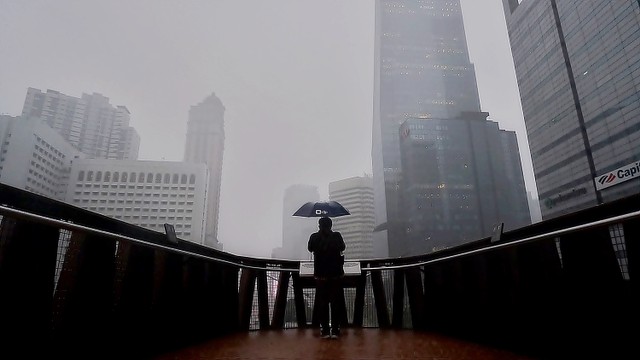 Warga menyebrangi Jembatan Penyeberangan Orang dan Sepeda (JPOS) Pinisi saat hujan deras di Sudirman, Jakarta, Jumat (11/3/2022). Foto: Jamal Ramadhan/kumparan