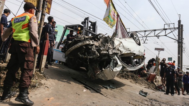 Petugas dengan bantuan alat berat melakukan evakuasi mobil yang tertabrak KRL di Kawasan Rawageni, Cipayung, Depok, Jawa Barat, Rabu (20/4/2022).  Foto: Asprilla Dwi Adha/ANTARA FOTO