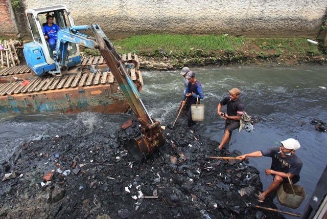 Petugas mengeruk endapan tanah dan lumpur di Kali Mampang, Jakarta, Senin (21/2/2022). Foto: Reno Esnir/ANTARA FOTO