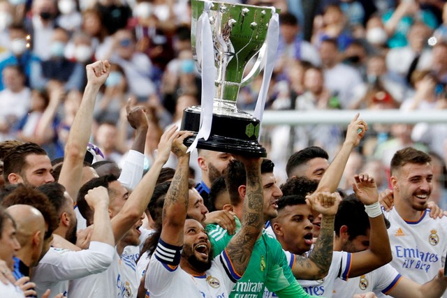 Pemain Real Madrid Marcelo memegang trofi dan merayakan dengan anggota tim setelah memenangkan LaLiga di Santiago Bernabeu, Madrid, Spanyol, Sabtu (30/4/2022). Foto: Susana Vera/REUTERS