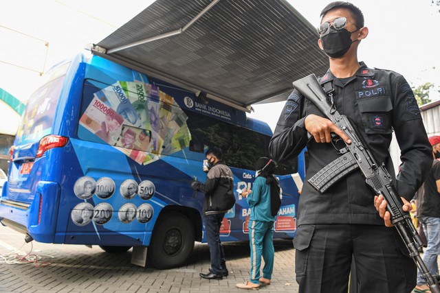 Seorang personel Satbrimob Polri berjaga saat berlangsungnya penukaran uang baru pada mobil kas keliling Bank Indonesia (BI) di Pasar Koja Baru, Jakarta Utara, Rabu (13/4/2022). Foto: M Risyal Hidayat/ANTARA FOTO