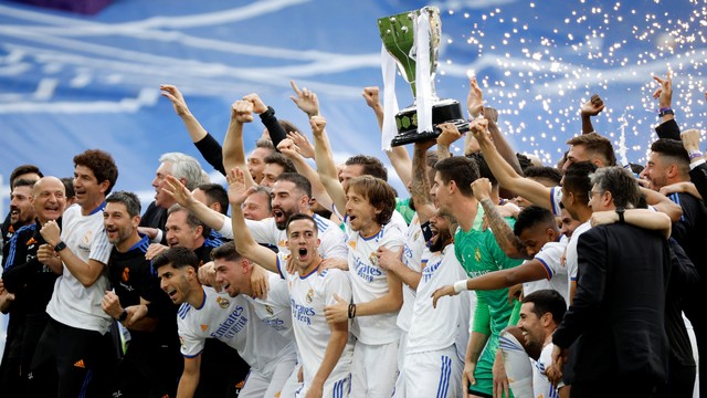 Pemain Real Madrid Marcelo memegang trofi dan merayakan dengan anggota tim setelah memenangkan LaLiga di Santiago Bernabeu, Madrid, Spanyol, Sabtu (30/4/2022). Foto: Juan Medina/REUTERS