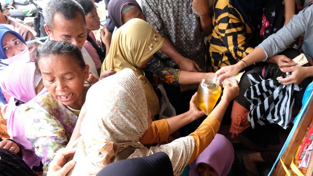 Sejumlah warga berebut membeli minyak goreng curah di sebuah toko sembako di kompleks pasar Bandongan, Magelang, Jawa Tengah, Sabtu (26/3/2022).