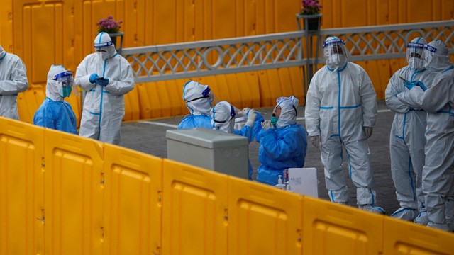 Polisi dan pekerja staf menjalani tes COVID-19 di dalam penghalang area yang dilockdown, di Shanghai, China, Kamis (24/3/2022) Foto: Aly Song/REUTERS