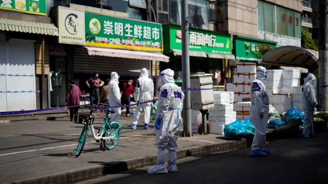 Polisi dan anggota keamanan dengan pakaian APD berdiri di luar toko makanan yang ditutup di Shanghai, China, Rabu (30/3/2022). Foto: Aly Song/REUTERS