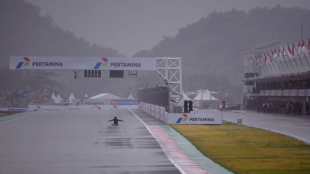 Penonton menunggu di tengah hujan saat ajang balap MotoGP Indonesia di Sirkuit Internasional Mandalika, Kuta, Lombok, Nusa Tenggara Barat pada Minggu (20/3/2022).
 Foto: Bay Ismoyo/AFP