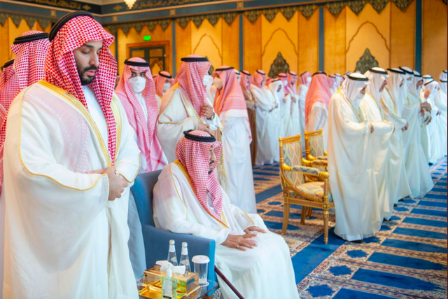 Pangeran MBS sedang salat (kiri) dan Raja Salman duduk di kursi di sebelahnya, pada salat Id 1 Syawal 1443 H di Masjidil Haram, Senin (2/5/2022). Foto: Makkah Region