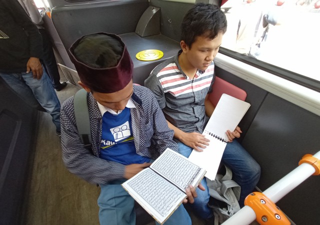 Febrian Valentino (kanan), remaja penyandang tunanetra ini terlihat khusyuk membaca Qur'an braille di atas Suroboyo Bus. Foto-foto: Masruroh/Basra