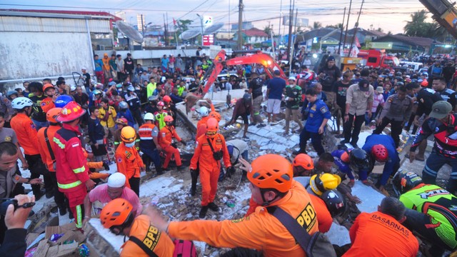 Tim SAR mengevakuasi korban yang terjebak di reruntuhan gedung retail modern Alfamart di Gambut Km 15, Kabupaten Banjar, Kalimantan Selatan, Senin (18/4/2022). Foto: Iman Satria/ANTARA FOTO