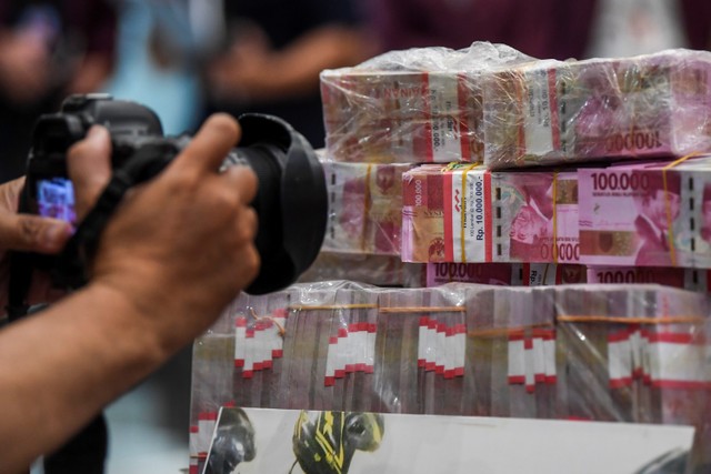 Pewarta foto memotret barang bukti mata uang rupiah palsu saat rilis pengungkapan kejahatan mata uang palsu di Bareskrim Mabes Polri, Jakarta, Selasa (1/3/2022). Foto: Galih Pradipta/ANTARA FOTO